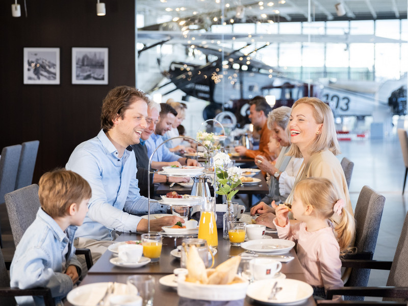 Eine Familie sitzt an einem Tisch und genießt ein gemeinsames Frühstück im Dornier Museum.
