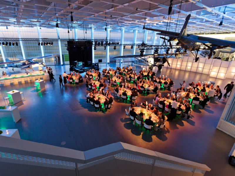 Der Hangar ist mit Tischen und Stühlen für ein Event ausgestattet.