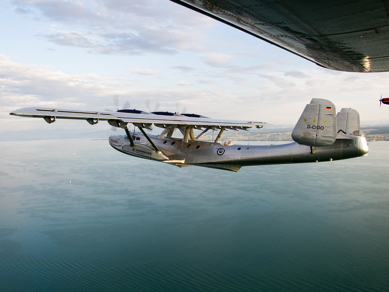 Historisches Militärflugzeug fliegt über das Meer, Sicht von einem anderen Flugzeug aus mit Flügel im Bild.