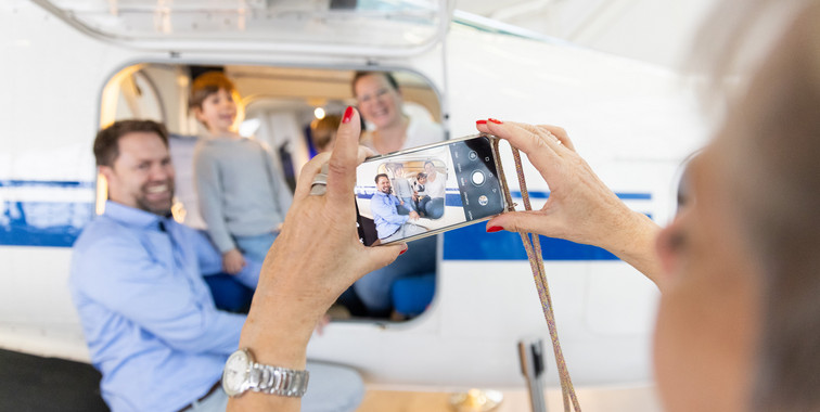 A Family of three is being photographed while sitting inside a small plane.