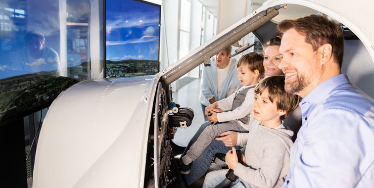 Besucher steuern ein Flugzeug in einem realistischen Flugsimulator.