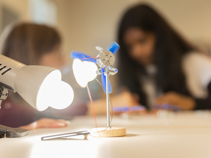 Ein Modell wird mit einer Lampe beleuchtet während Schüler im Hintergrund arbeiten.