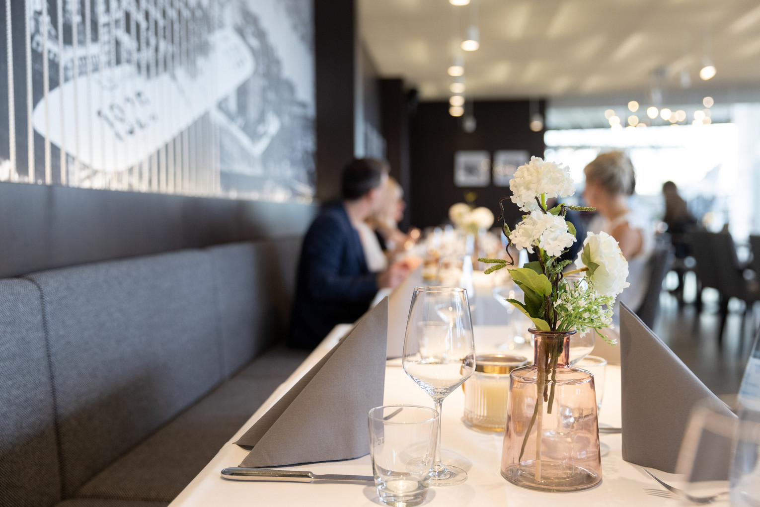 Gedeckter Tisch im Dornier-Restaurant mit Gästen im Hintergrund.