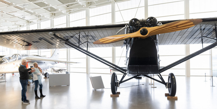 A black plane in the hangar of die Museum with two visitors on the left of the picture.
