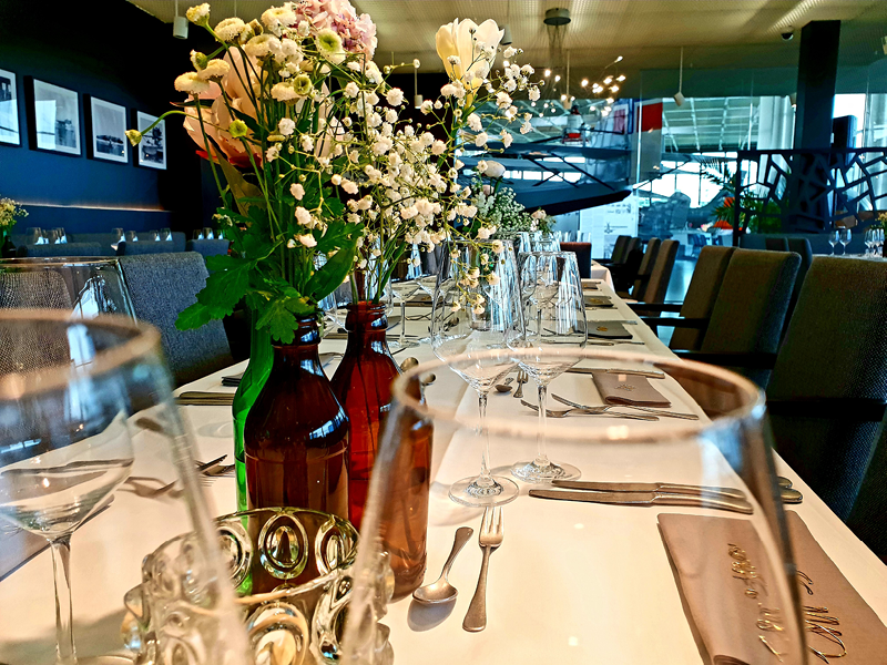 Ein festlich gedeckter Tisch mit Blumenschmuck, zwei Weingläser stehen im Vordergrund.