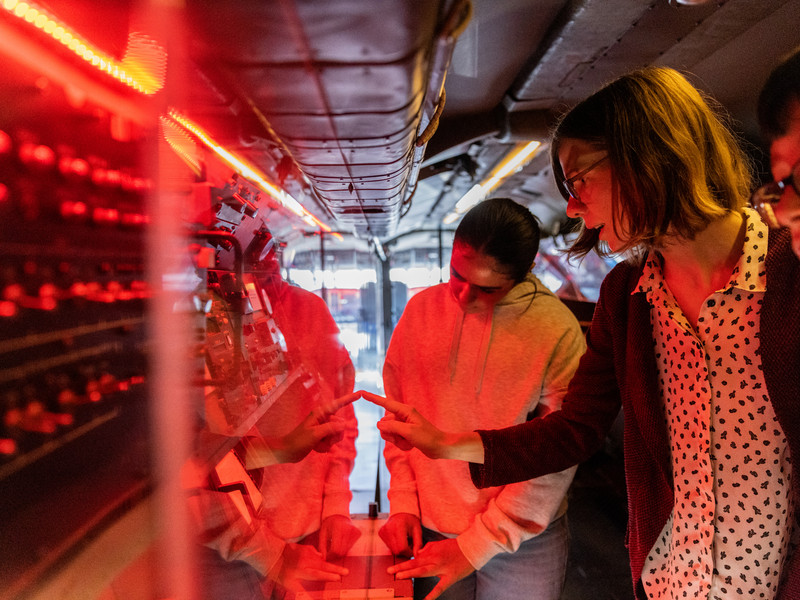 Schüler betrachten ein beleuchtetes Ausstellungsstück.